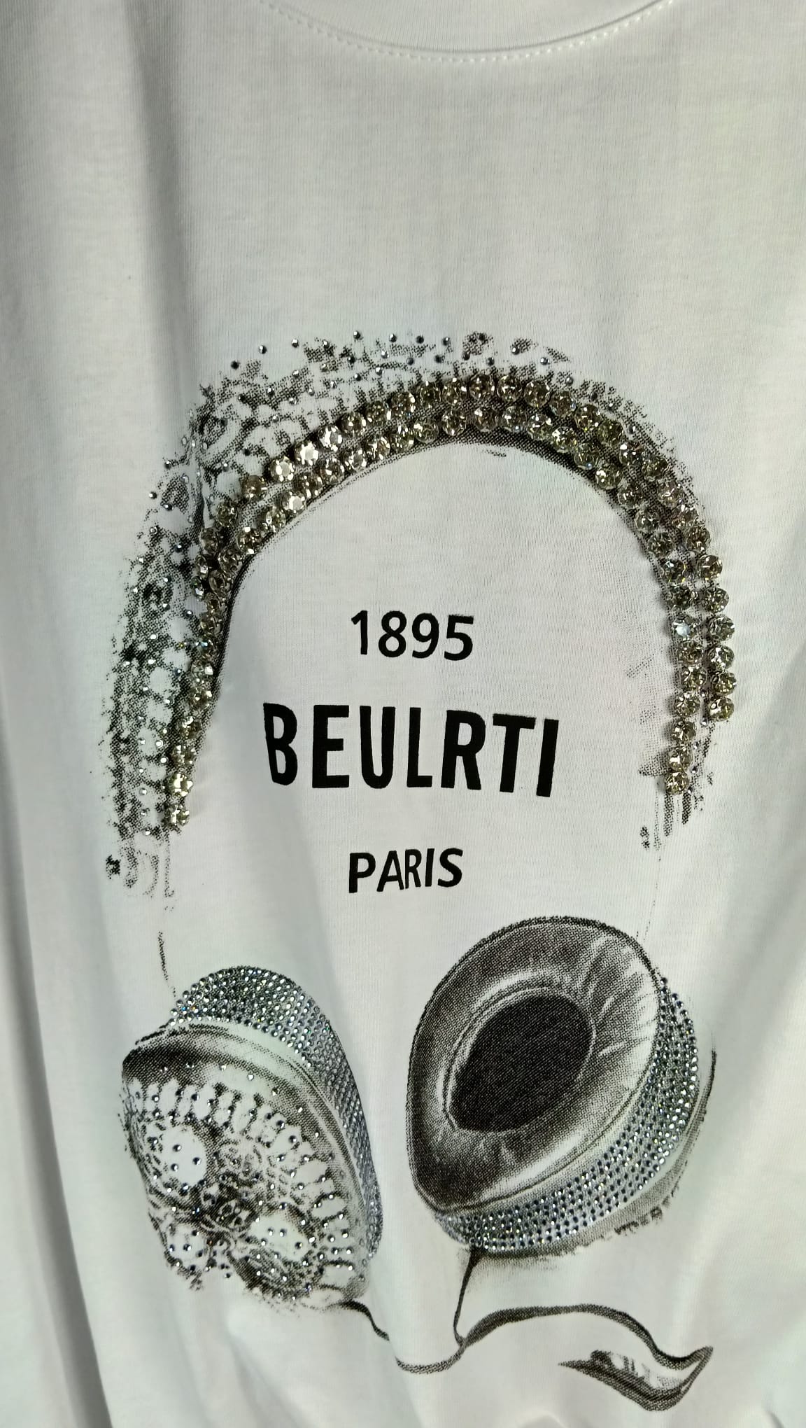 Detalle del diseño de auriculares con strass de la camiseta blanca